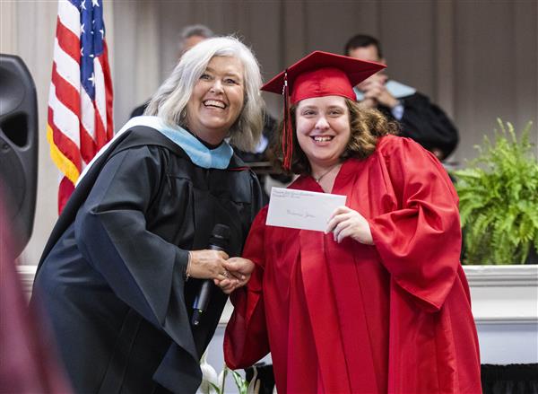 A 2023 Graduate from Helen Keller School of Alabama accepts an award from Amy Shelly, Academic Director.